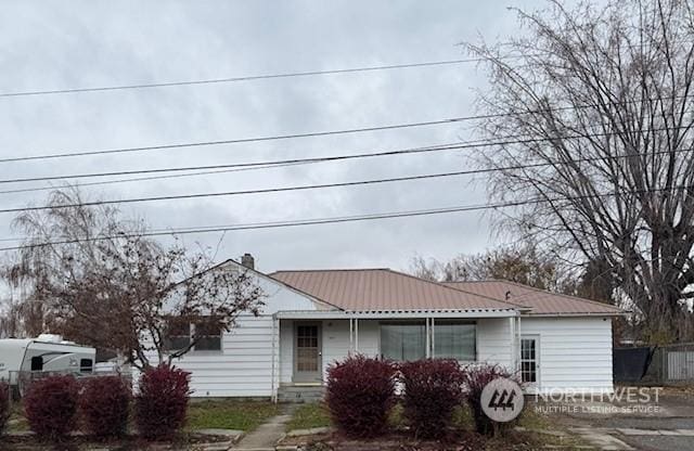 ranch-style house with metal roof and fence