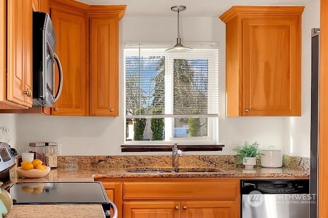 kitchen with light stone counters, sink, hanging light fixtures, and appliances with stainless steel finishes