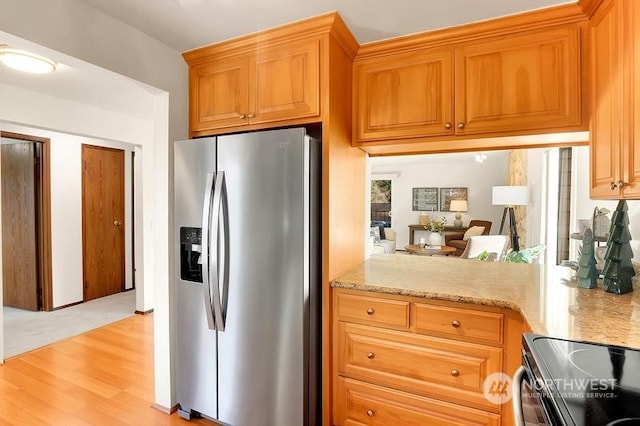 kitchen with light stone countertops, stainless steel appliances, and light hardwood / wood-style flooring