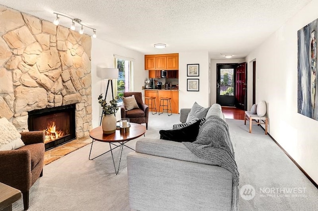 living room with a stone fireplace, light colored carpet, and a textured ceiling