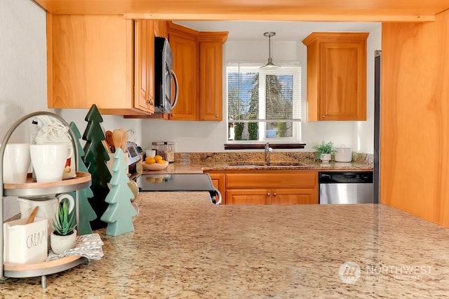 kitchen featuring light stone countertops, appliances with stainless steel finishes, decorative light fixtures, and sink