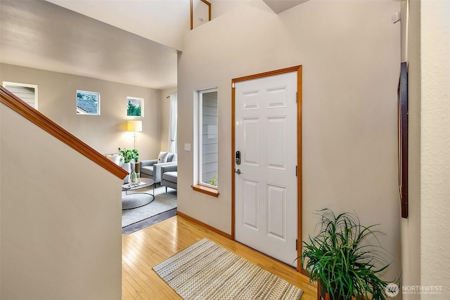 foyer entrance featuring baseboards, light wood finished floors, and stairs