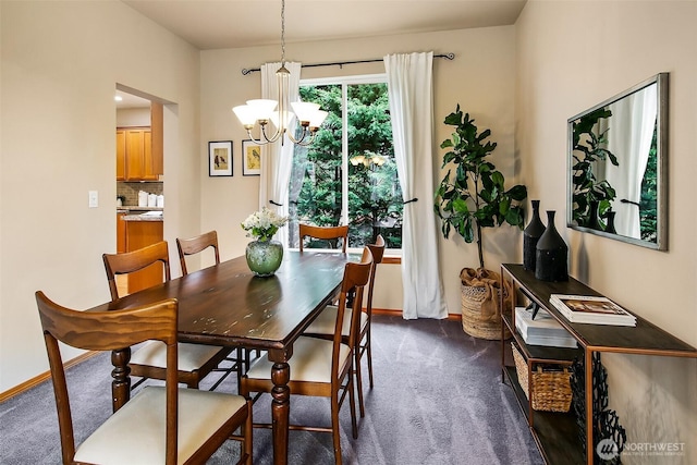 dining room with a chandelier, dark carpet, and baseboards