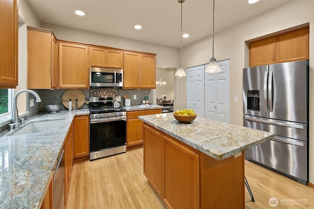 kitchen with stainless steel appliances, a kitchen island, a sink, light wood-style floors, and tasteful backsplash