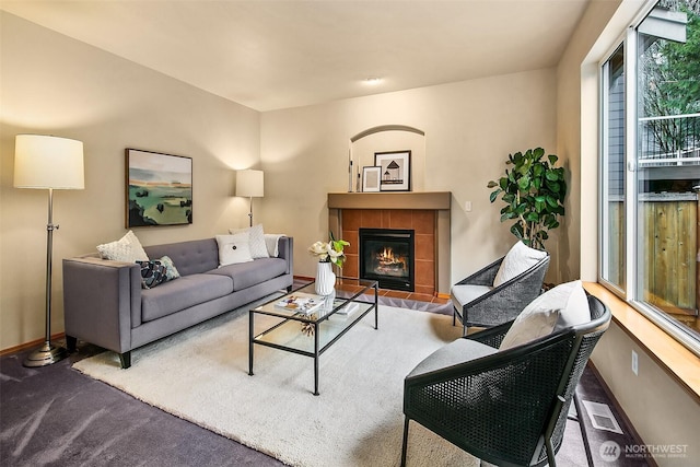 living room featuring a fireplace, carpet flooring, visible vents, and baseboards