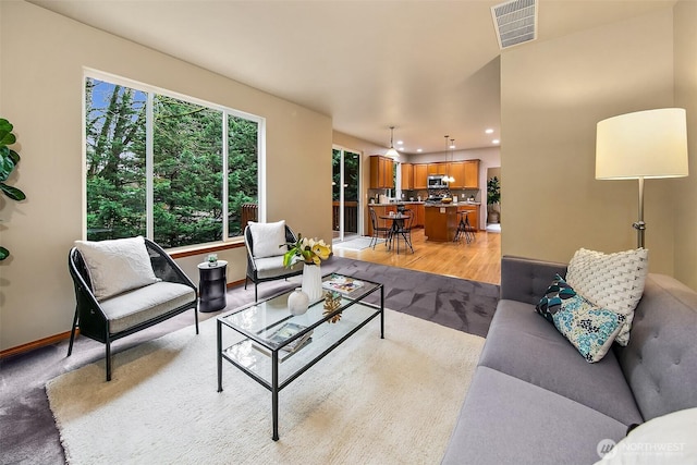 living room featuring light carpet, baseboards, visible vents, and recessed lighting