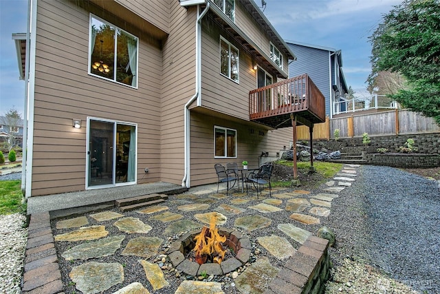 back of property with a fire pit, a deck, a patio area, and fence