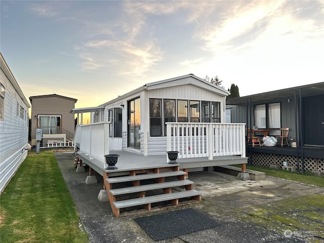 back house at dusk with a sunroom and a deck