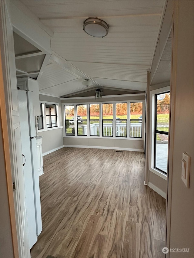 unfurnished sunroom featuring vaulted ceiling with beams and a wealth of natural light