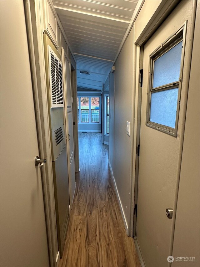 corridor with hardwood / wood-style floors and lofted ceiling