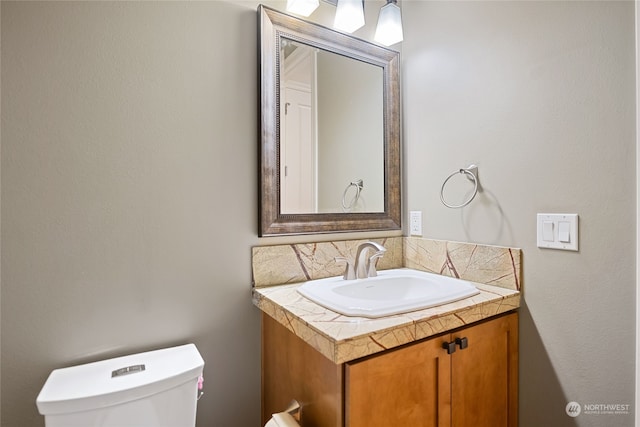 bathroom with vanity, toilet, and backsplash