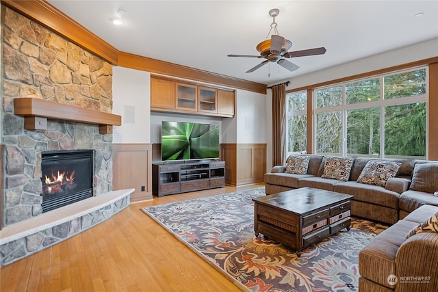 living room featuring ceiling fan, a stone fireplace, and wood-type flooring