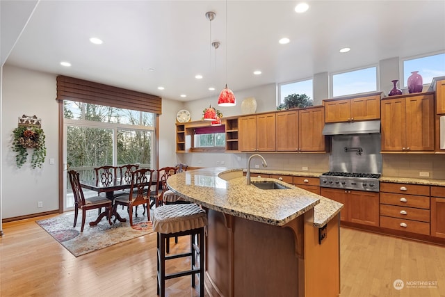 kitchen with a breakfast bar, light wood-type flooring, sink, and hanging light fixtures