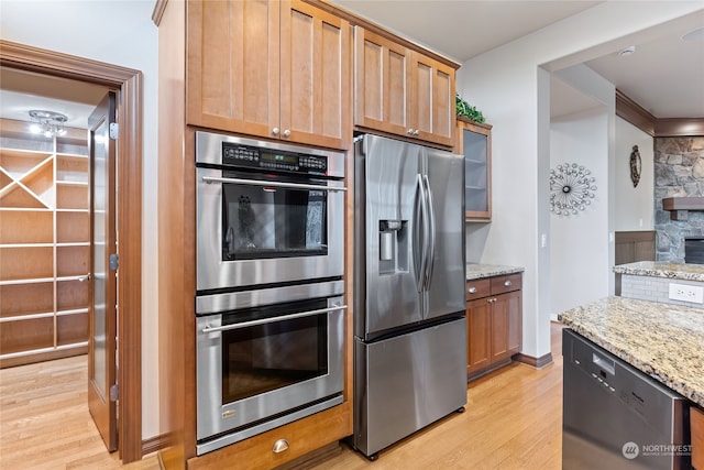 kitchen featuring stainless steel appliances, light hardwood / wood-style flooring, and light stone counters