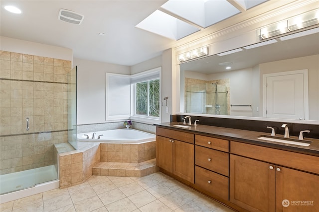 bathroom featuring tile patterned flooring, vanity, independent shower and bath, and a skylight