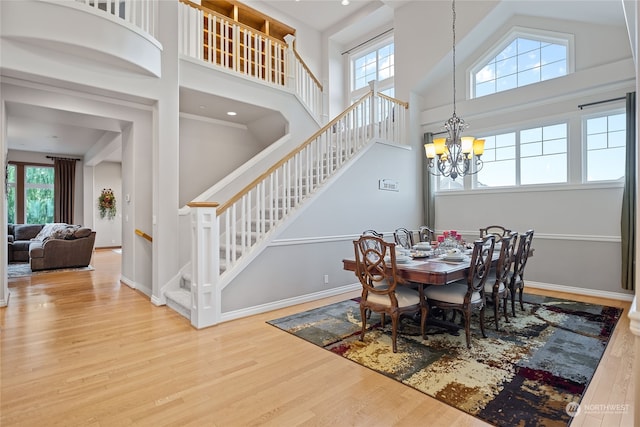 dining space with hardwood / wood-style floors, high vaulted ceiling, and an inviting chandelier