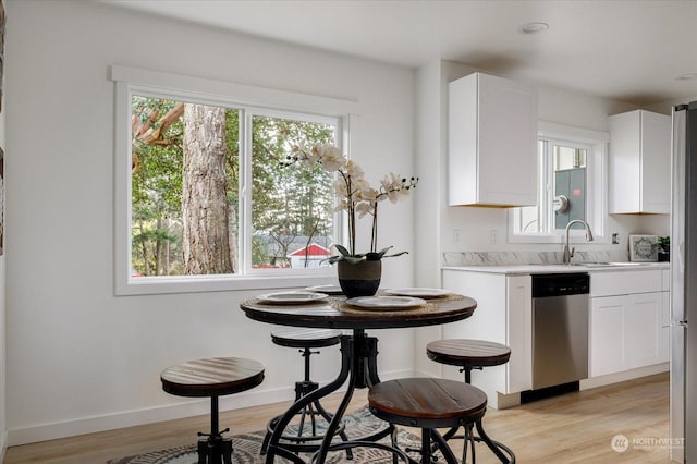 kitchen featuring white cabinetry, dishwasher, light hardwood / wood-style floors, and sink