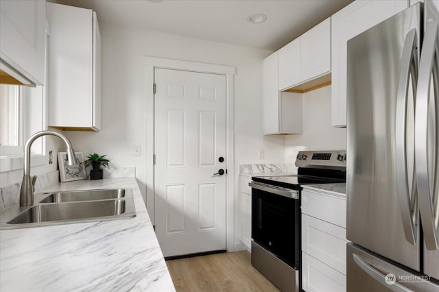 kitchen featuring sink, white cabinets, light wood-type flooring, and appliances with stainless steel finishes