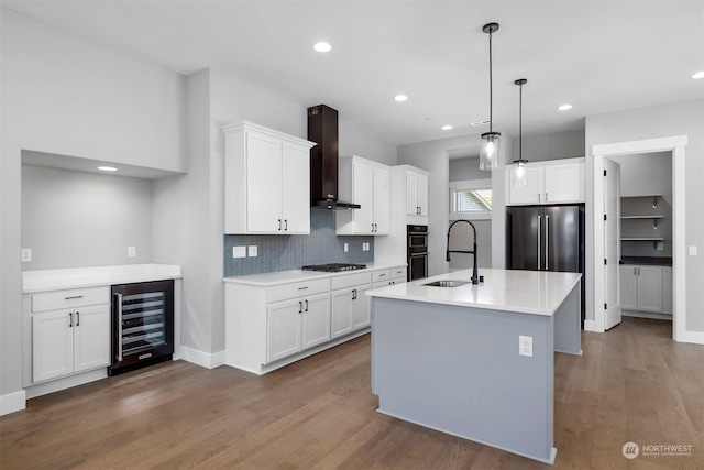 kitchen with sink, wall chimney exhaust hood, appliances with stainless steel finishes, white cabinetry, and beverage cooler