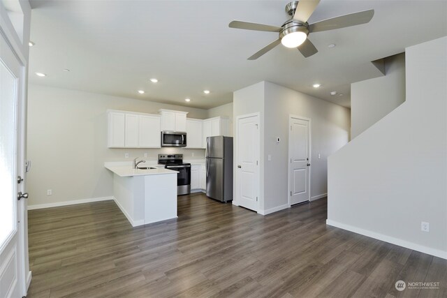 kitchen with white cabinets, stainless steel appliances, kitchen peninsula, and dark wood-type flooring