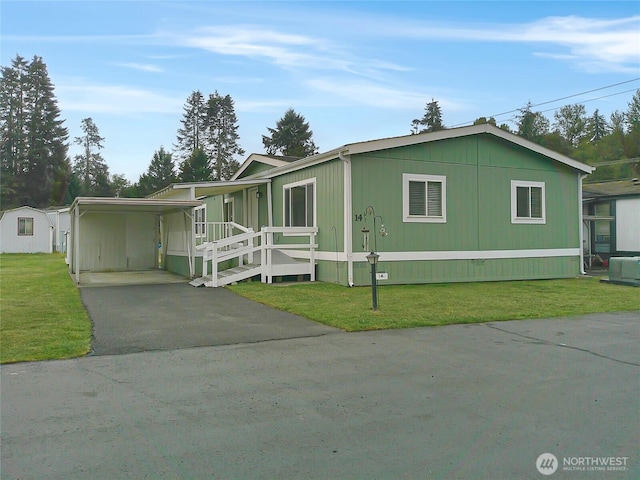 view of front of house featuring aphalt driveway, an attached carport, central AC unit, and a front yard