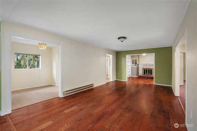 unfurnished living room with baseboard heating, a fireplace, and wood-type flooring