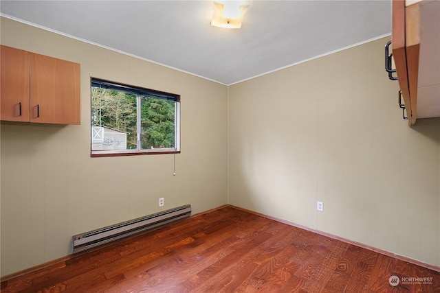 unfurnished room featuring hardwood / wood-style flooring, baseboard heating, and ornamental molding