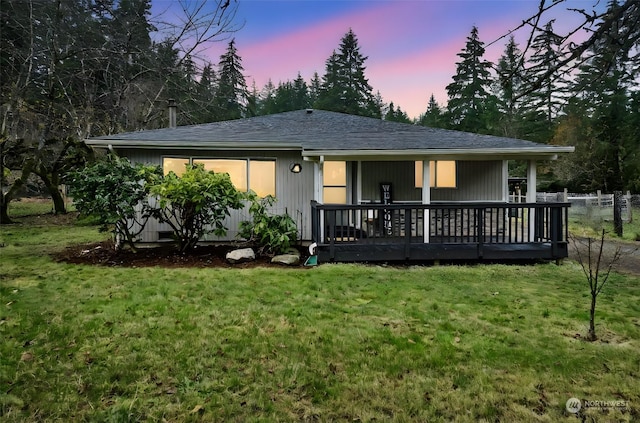 back house at dusk featuring a lawn