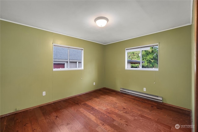 spare room with crown molding, wood-type flooring, and baseboard heating