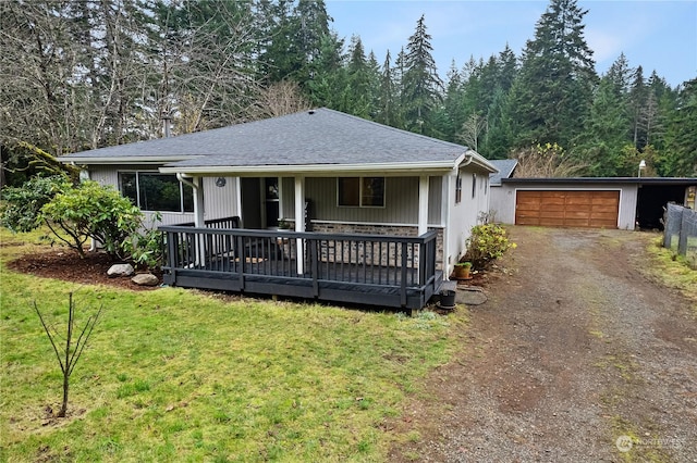 view of front facade with an outbuilding, a porch, a garage, and a front lawn