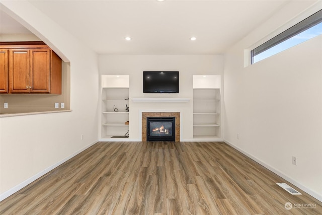 unfurnished living room with hardwood / wood-style flooring and a tiled fireplace