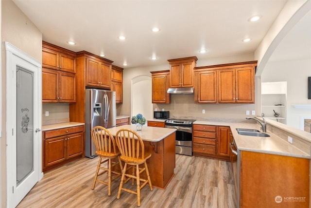 kitchen with sink, stainless steel appliances, kitchen peninsula, light hardwood / wood-style floors, and a breakfast bar