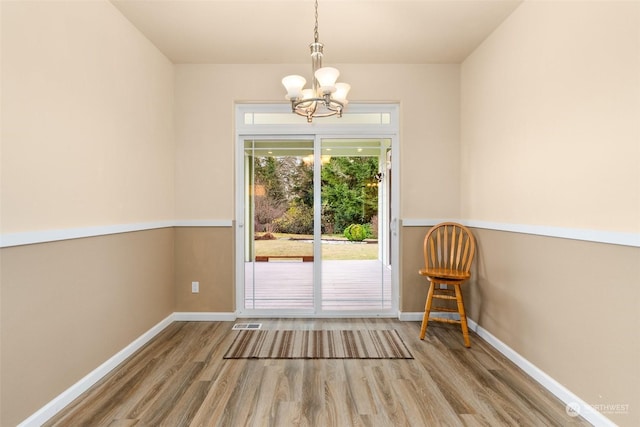 unfurnished dining area with a chandelier and wood-type flooring