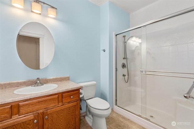 bathroom featuring tile patterned floors, vanity, toilet, and a shower with shower door