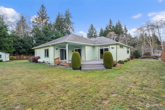 rear view of house featuring a lawn, a wooden deck, and a storage shed