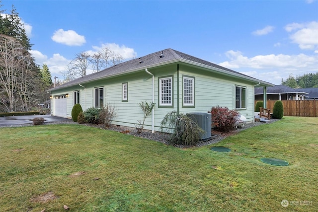 view of property exterior featuring central AC unit, a garage, and a yard