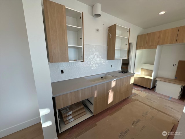 kitchen featuring light wood-type flooring, decorative backsplash, light brown cabinets, and sink