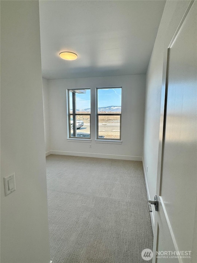 carpeted empty room featuring baseboards