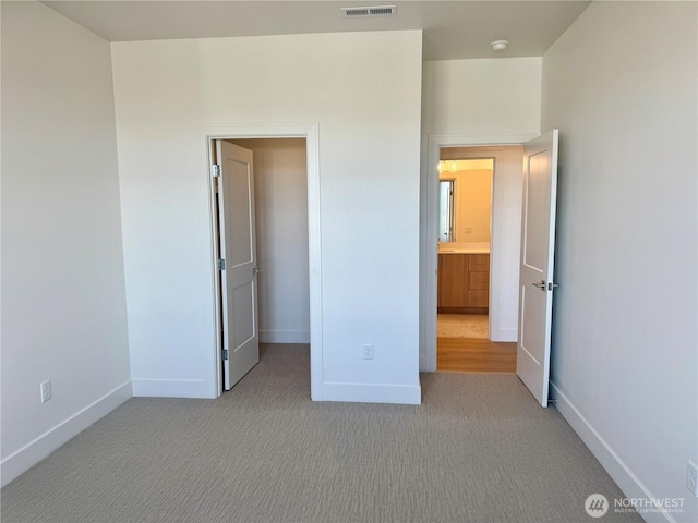 unfurnished bedroom with visible vents, a spacious closet, baseboards, and carpet flooring