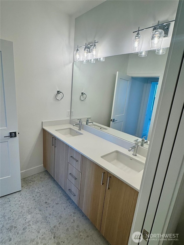 full bathroom with double vanity, baseboards, and a sink