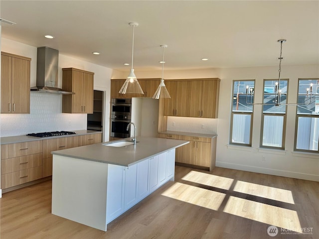 kitchen with wall chimney range hood, double oven, modern cabinets, and a sink