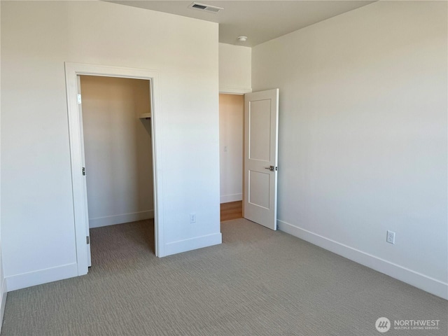 unfurnished bedroom with light carpet, baseboards, a spacious closet, and visible vents