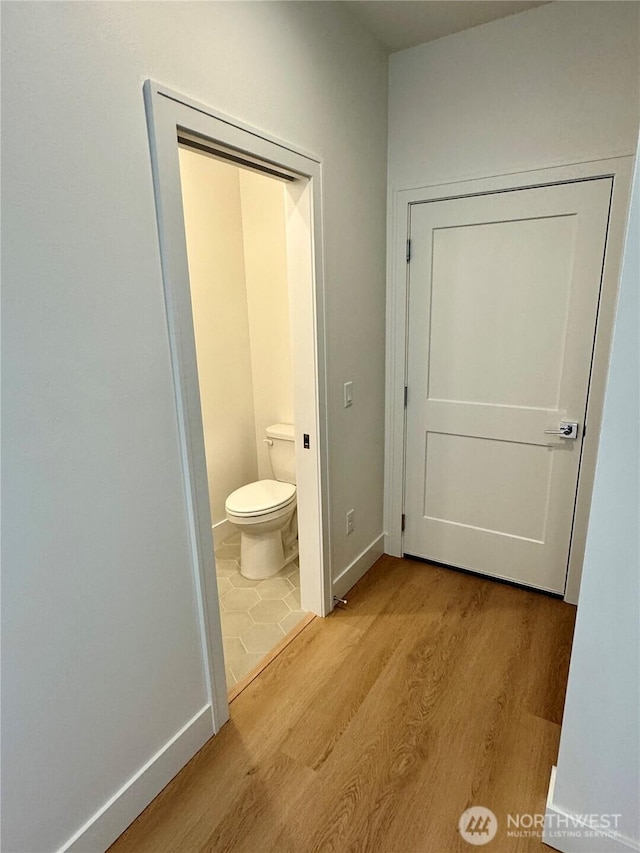 bathroom with toilet, baseboards, and wood finished floors