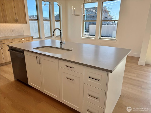 kitchen featuring dishwasher, light wood-style flooring, a kitchen island with sink, white cabinetry, and a sink