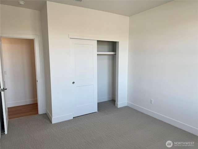 unfurnished bedroom with carpet floors, a closet, and baseboards