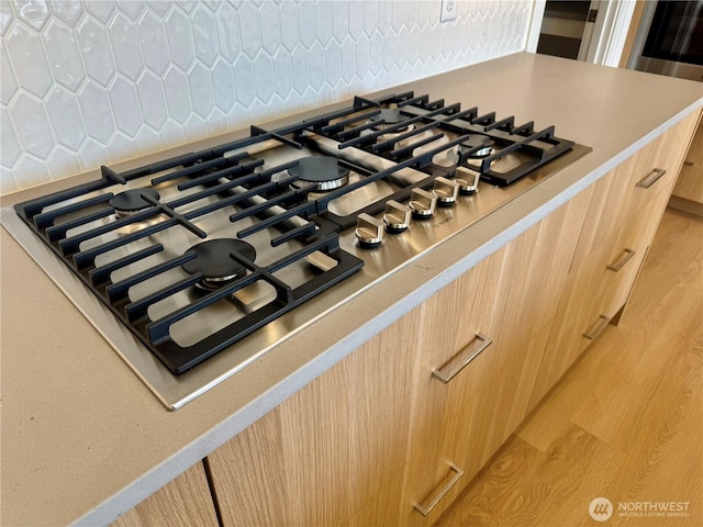 room details with modern cabinets, light countertops, stainless steel gas cooktop, and light brown cabinetry