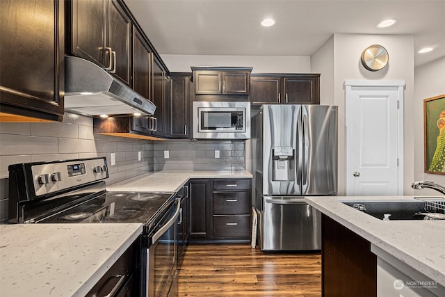 kitchen featuring light stone countertops, dark hardwood / wood-style flooring, dark brown cabinets, stainless steel appliances, and sink