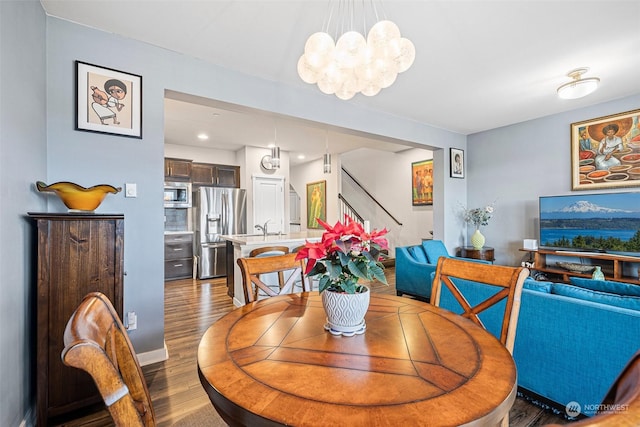 dining area with dark hardwood / wood-style floors, an inviting chandelier, and sink