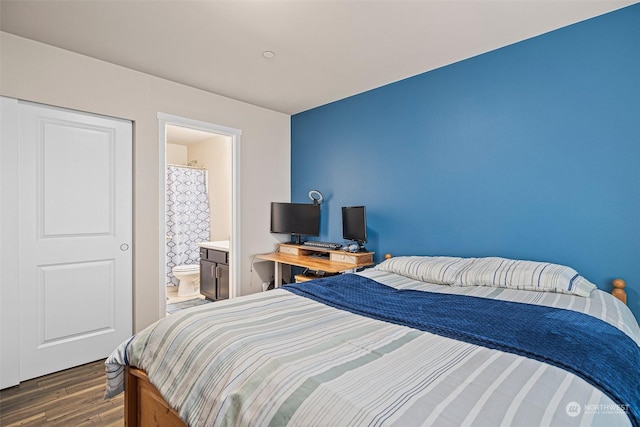 bedroom with ensuite bathroom and dark wood-type flooring