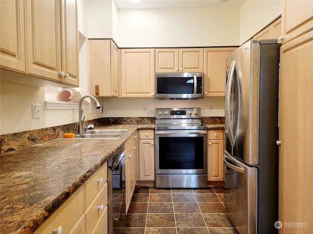 kitchen with sink, stainless steel appliances, dark stone countertops, and light brown cabinets